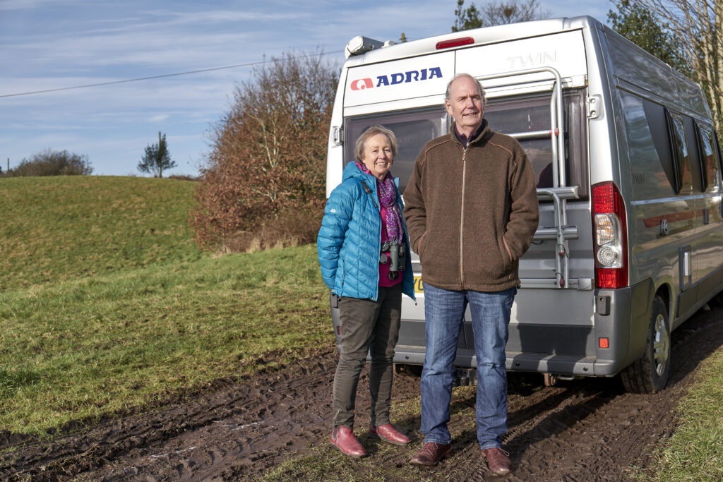 Example photo of two dementia research volunteers stood outside in a field in front of a campervan
